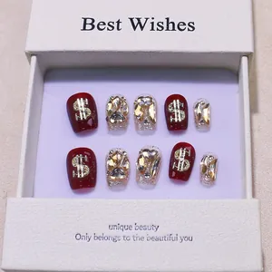 Handmade cherry red press-on nails with silver glitter, dollar charms, and rhinestones