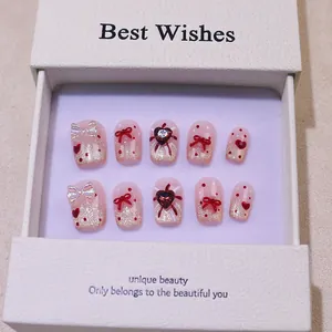 Faux ongles dégradé rose avec nœuds rouges et cœurs dans un coffret cadeau blanc
