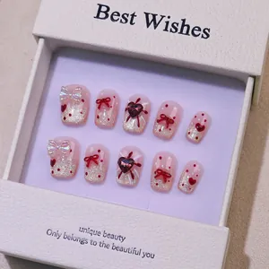 Vue détaillée de 10 faux ongles faits main avec paillettes, nœuds et motifs à pois