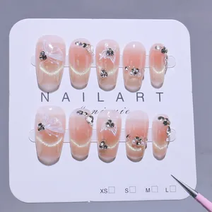 Handmade press-on nails with pink cat-eye gradient effect and butterfly rhinestone accents