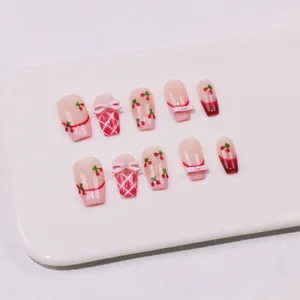 Detail handgefertigter Kirsch-Nägel mit rosa Schleifen und französischem Karomuster