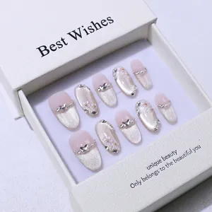 Vue macro détaillée de faux ongles faits main style œil de chat avec cœur argenté et perles