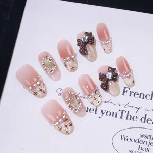 Faux ongles faits main dégradé rose nude avec nœud, perles et motifs pailletés
