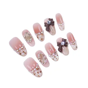 Faux ongles dégradés roses avec nœuds 3D marron, perles et strass brillants