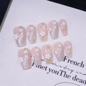 Pink cat-eye press-on nails with 3D white flowers and gold bead accents in coffin shape