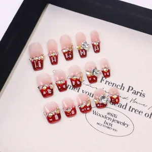 Handmade French press-on nails set with red glitter, rhinestones, and pearls on white board