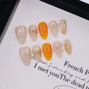 Handmade almond press-on nails with 3D floral relief, orange spiral texture, and pearls