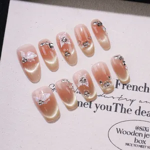 Unghie finte fatte a mano nude con glitter cat-eye, farfalle dipinte e strass scintillanti