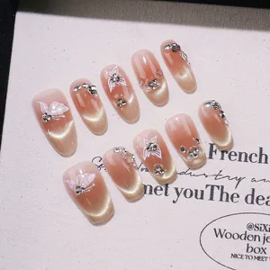 Unghie finte fatte a mano nude cat eye con decorazioni a farfalla e strass luminosi