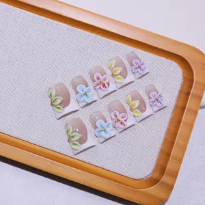 Macro view of handmade press-on nails with 3D embossed flowers and French white tips