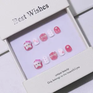 Pink and white handmade press-on nails for kids with cute bows and stars in a gift box