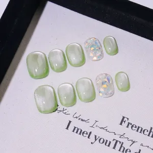 Faux ongles faits main effet œil de chat vert clair avec paillettes et strass