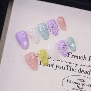 Detail of handmade almond nails featuring 3D floral carvings and pearl embellishments