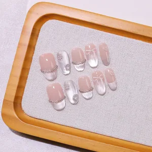 Faux ongles faits main rose nude avec effet œil de chat argenté et nœuds en perles
