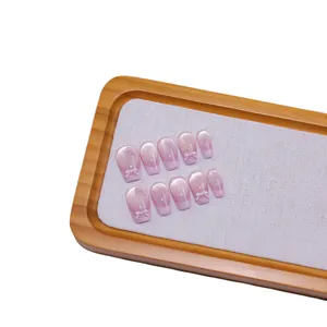 Purple cat eye gradient press-on nails with 3D ribbon bows on a wooden display tray