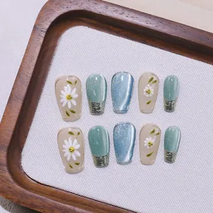 Unghie finte fatte a mano con fiori 3D ed effetto cat-eye su vassoio di legno