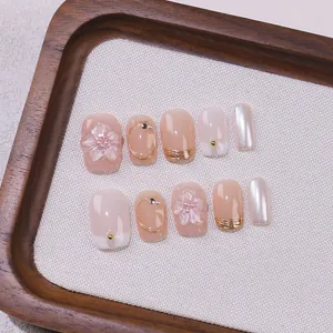 Handmade press-on nails with 3D embossed flowers and gold foil on soft pink gradient