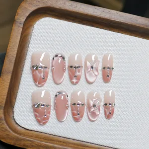 Faux ongles amande faits main avec dégradé rose, papillon 3D et décorations en strass