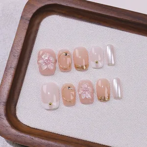 3D floral relief press-on nails with pink gradient and pearl accents on wooden tray