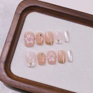Press-on nail set with 3D floral relief and golden metallic accents on pink gradient