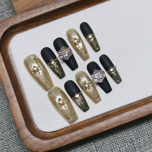 Handmade matte black and gold coffin press-on nails with 3D snowflake and rhinestone decor