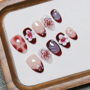 Handmade press-on nails featuring burgundy floral 3D relief and rhinestone accents