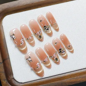 Handmade almond press-on nails with pink cat-eye gradient, crystal butterfly, and pearls