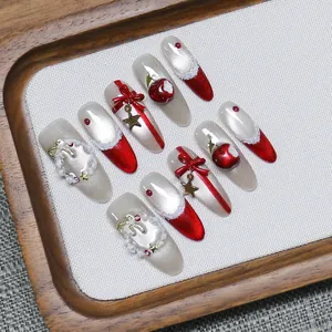 Handmade Christmas press-on nails with red bows and gold charms in almond shape