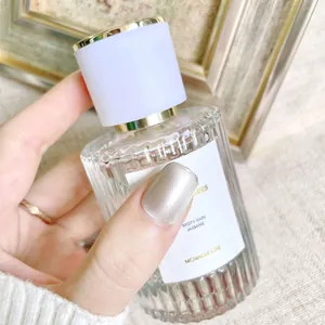 Hand holding Misty Rain Jasmine perfume bottle with cat eye nail art and gold ring