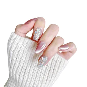 Pink cat eye press-on nails with silver glitter and butterfly sequins on model hand
