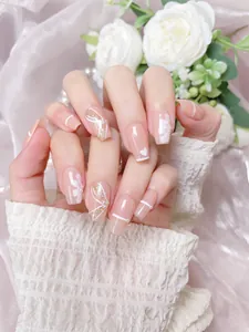 Close-up of handmade press-on nails with nude pink base, floral art and pearl accents