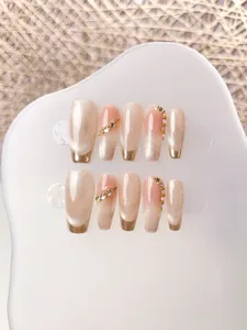 Detail of handmade champagne cat eye press-on nails with rhinestones and gold edges