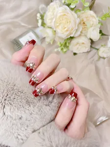 Vue détaillée de faux ongles faits main bordeaux avec des strass étincelants et des perles
