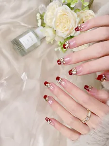 Gros plan d'ongles trapèze longs à presser avec effet œil de chat rouge et strass luxueux