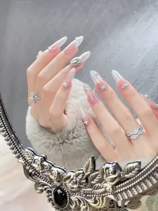 Close-up of almond-shaped press-on nails with glitter gradient and rhinestone pearls