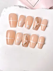 Detail of handmade nude press-on nails with 3D pearls, white floral art, and gold glitter