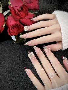Dettaglio di unghie finte French con fiocchi avorio, perle e strass luccicanti