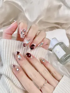 Detail of handmade press-on nails featuring red gems, silver sequins and blue heart charms