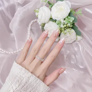 Nude pink press-on nails with white ribbons and 3D bows shown on model's hand