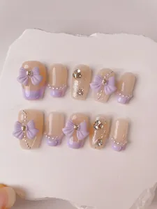 Close-up of handmade press-on nails with 3D purple bows, pearls and glitter accents