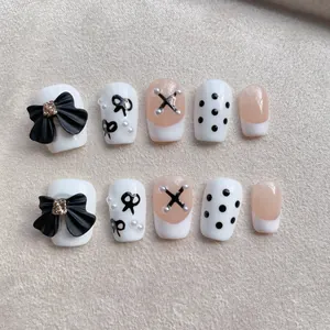 Handmade press-on nails with black 3D bows, pearls, and French nude style manicure