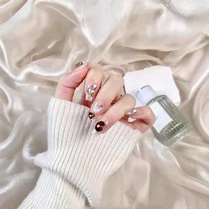 Luxurious handmade press-on nails with red crystals and pearls on silk background