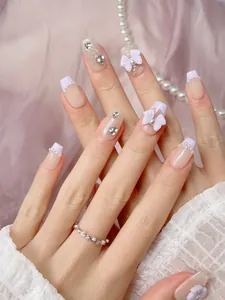 Close-up of handmade press-on nails with lavender tips, 3D bows, and pearl details