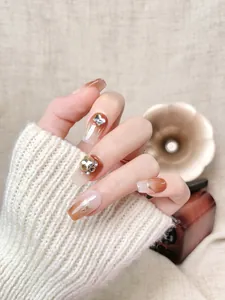 Detailed view of amber gradient press-on nails with metal butterflies and rhinestones