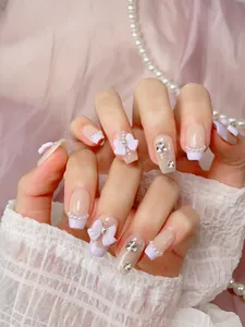 Macro shot of handmade purple French nails with 3D bows, pearls and sparkling rhinestones