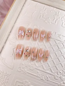 Detail of pink press-on nails featuring 3D butterflies and rhinestone flower patterns