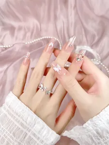 Detail of pink cat-eye press-on nails with 3D butterfly, glitter, and silver accents