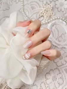 Close-up of French cat-eye press-on nails with white swan art and sparkling rhinestones