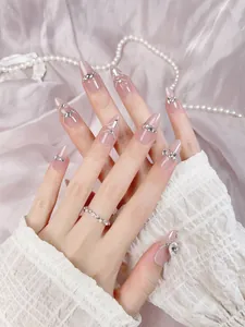 Detail of almond-shaped press-on nails in nude pink with sparkling rhinestones and gems