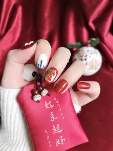 Macro shot of red and white handmade press-on nails with golden festive Na Fu lettering
